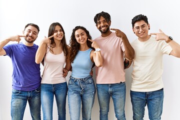 Group of young people standing together over isolated background smiling cheerful showing and...
