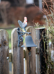 Eine Glocke mit einem Hahn an einem Gartentor.