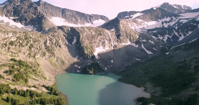 Atmospheric and moody aerial drone video footage of turquoise Krepkoe Lake at sunset in Altai, Russia. National park and natural wonders background