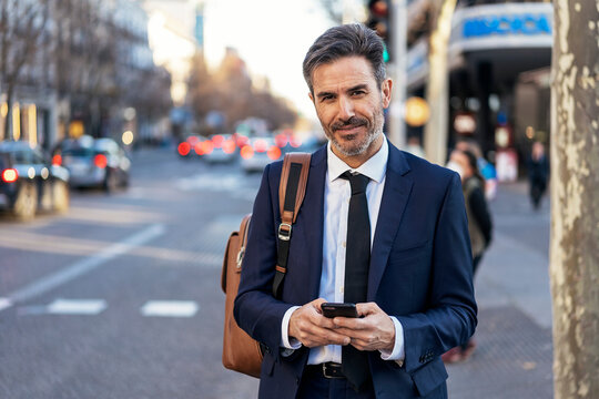 Mature businessman using smartphone on street