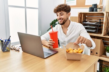 Fototapeta na wymiar Young arab man using laptop having lunch at office