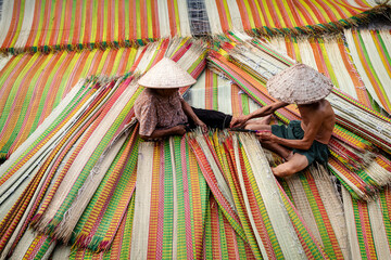 Vietnamese Old Man and Women Making a drying traditional vietnam mats in the old traditional...