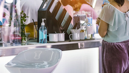 Blue alcohol gel bottle for hand cleaning to prevent the spreading of the Coronavirus (Covid-19) on counter to service for customers at cafe or coffee shop. Healthcare concept. New normal lifestyle.
