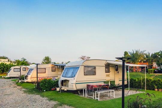 Cozy retro travel trailer Caravan on green grass before sunset near riverside in peaceful countryside. Family vacation travel RV, holiday trip in motorhome. Outdoor and Recreational Vehicles Theme.