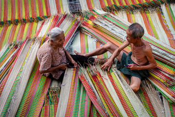 Vietnamese Old Man and Women Making a drying traditional vietnam mats in the old traditional village at dinh yen, dong thap, vietnam, tradition artist concept,Vietnam.