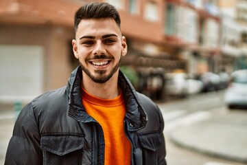 Obraz premium Handsome hispanic man with beard smiling happy and confident at the city wearing winter coat