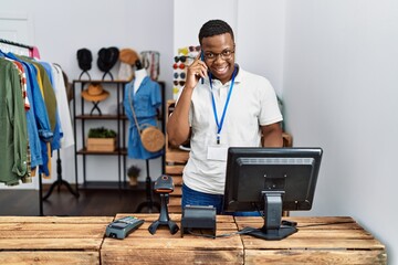 Young african man working as shop assistance speaking on the phone at retail shop