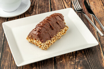 Dessert Cake from Malaga on wooden table. Cake with banana inside, covered with chocolate sauce and hazelnuts.