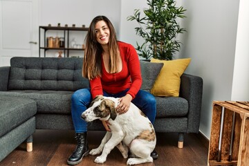Young woman hugging dog sitting on sofa at home