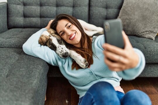 Young woman hugging dog making selfie by the smartphone at home