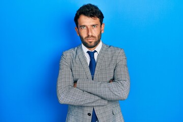 Handsome man with beard wearing business suit and tie skeptic and nervous, disapproving expression on face with crossed arms. negative person.
