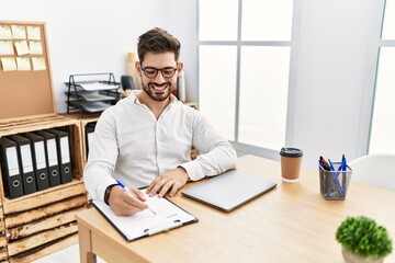Young hispanic businessman smiling happy working at the office.