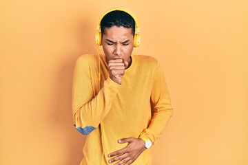 Young african american guy listening to music using headphones feeling unwell and coughing as symptom for cold or bronchitis. health care concept.