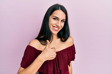 Young hispanic woman wearing casual clothes doing happy thumbs up gesture with hand. approving expression looking at the camera showing success.