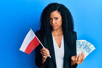 Middle age african american woman holding poland flag and zloty banknotes skeptic and nervous, frowning upset because of problem. negative person.