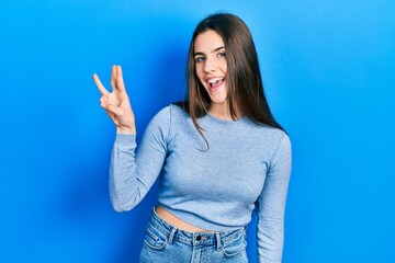Fototapeta na wymiar Young brunette teenager wearing casual sweater showing and pointing up with fingers number three while smiling confident and happy.