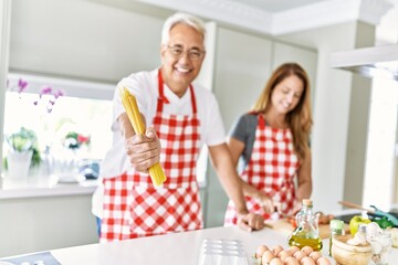 Middle age hispanic couple smiling happy cooking at the kitchen.