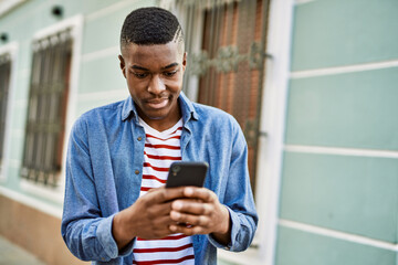 Young african american man smiling happy using smartphone at the city.