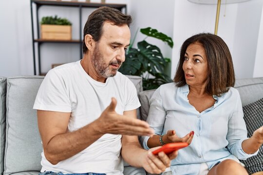Middle age man and woman couple with problem for infidelity using smartphone at home
