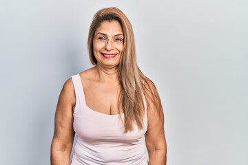 Middle age hispanic woman wearing casual style with sleeveless shirt smiling looking to the side and staring away thinking.