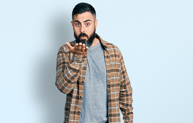Hispanic man with beard wearing casual shirt looking at the camera blowing a kiss with hand on air being lovely and sexy. love expression.