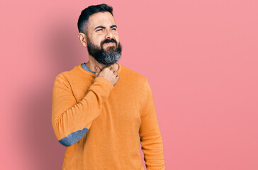 Fototapeta premium Hispanic man with beard wearing casual winter sweater touching painful neck, sore throat for flu, clod and infection
