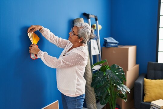 Middle age woman choosing test paint color at new home