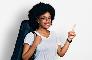 Young african american woman wearing guitar case smiling happy pointing with hand and finger to the side