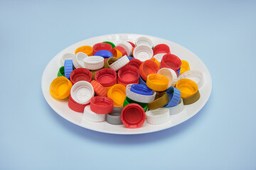 waste plastic lids in a white plate on a blue background, the concept of recycling, zero waste production