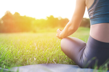 Rear view of a woman doing yoga in nature. Young woman sitting in lotus position at sunset