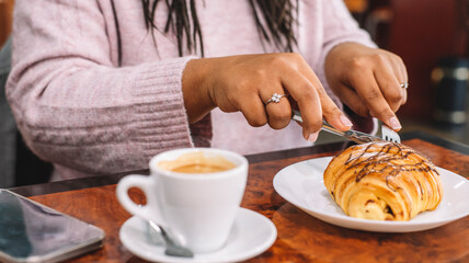 Young woman having breakfast with croissant and coffee