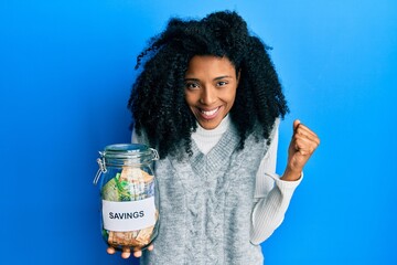 African american woman with afro hair holding savings jar with south african rands money screaming...