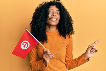 African american woman with afro hair holding turkey flag smiling happy pointing with hand and finger to the side