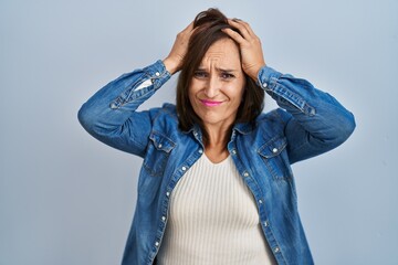 Middle age brunette woman wearing casual denim jacket over isolated background suffering from headache desperate and stressed because pain and migraine. hands on head.