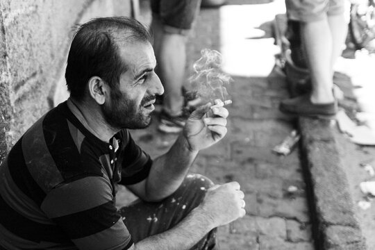 Closeup shot of a thoughtful smoking male outdoors on a grayscale in Istanbul, Turkey