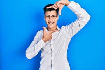 Young hispanic man wearing casual clothes and glasses smiling making frame with hands and fingers with happy face. creativity and photography concept.