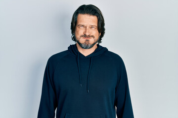 Middle age caucasian man wearing casual sweatshirt puffing cheeks with funny face. mouth inflated with air, crazy expression.