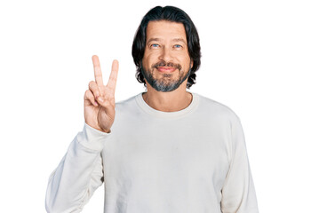 Middle age caucasian man wearing casual clothes showing and pointing up with fingers number two while smiling confident and happy.