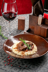 Milanese risotto with beef stew on a plate with red wine. Italian cuisine dish with rice and beef meat in sauce