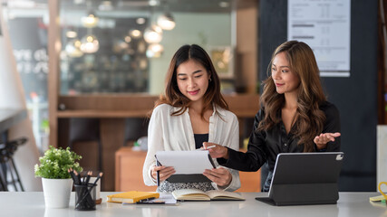 Two young Asian businesswoman analyzes, discusses plan marketing for collaboration in the office.