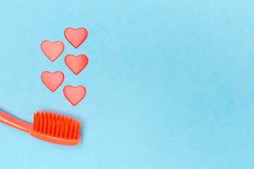 Toothbrush and hearts on blue background. Place for text. Copy space. Flat lay. Top view. Dental care kit. Oral hygiene.
