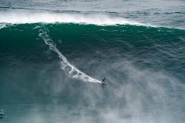 Professional athlete surfing a giant wave.