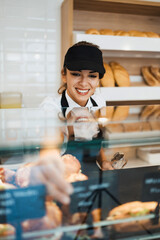 Beautiful young and happy female worker working in a modern bakery or fast food restaurant.