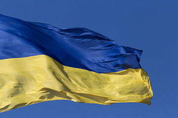 waved Ukrainian state flag against blue sky