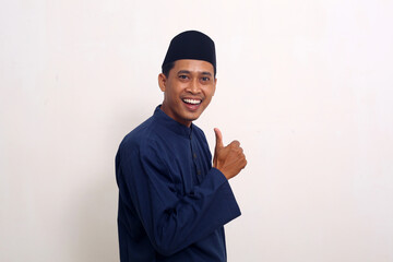 Asian muslim man standing and showing a thumbs up. Isolated on white