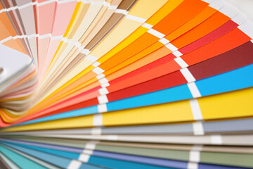 Color guide close up. Assortment of colors for design. Colors palette fan on white concrete wall...