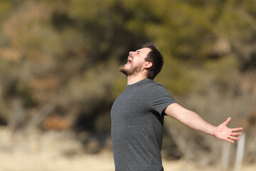 Excited man screaming in nature outstretching arms