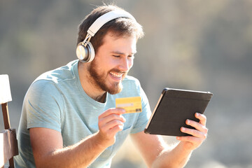 Happy man buying music with a tablet online