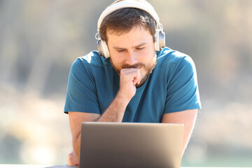 Man listening and watching videos on laptop outdoors