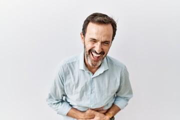 Middle age hispanic man with beard standing over isolated background smiling and laughing hard out loud because funny crazy joke with hands on body. - obrazy, fototapety, plakaty